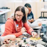 several adult at a table tinkering with materials