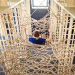 tween boy in blue shirt going downward in a rope net structure