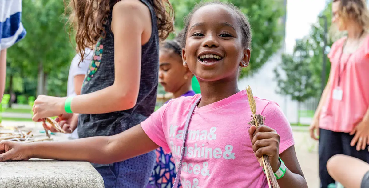 girl outside in park in summer, laughing and holding sticks