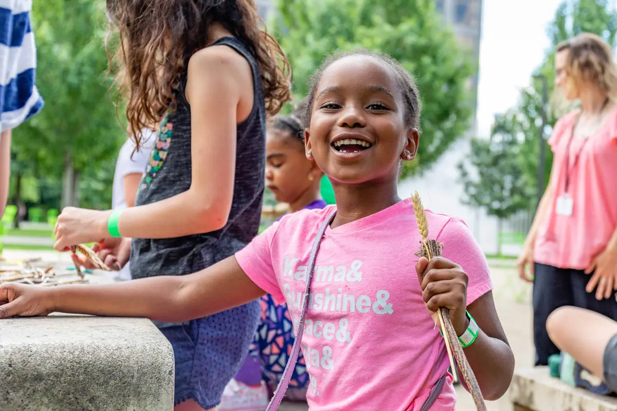 girl outside in park in summer, laughing and holding sticks