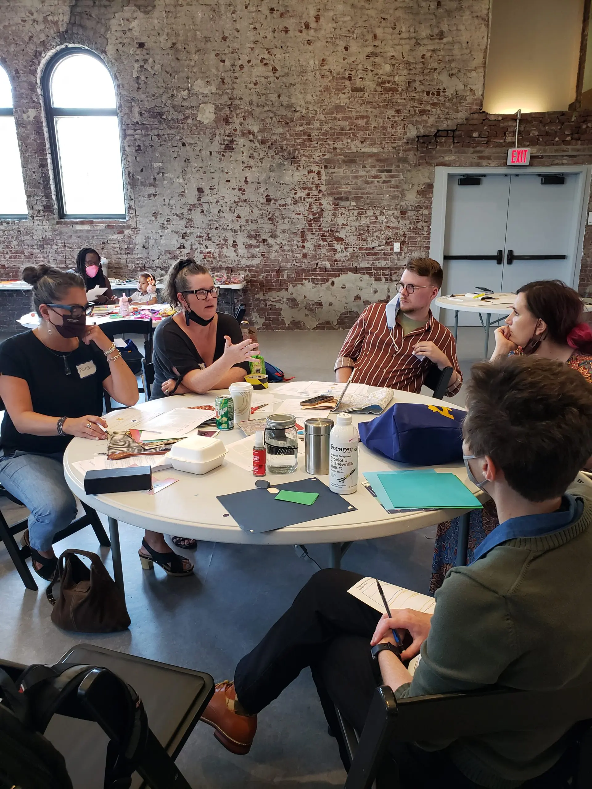 Educators collaborating at a circular table while making books.