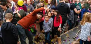 family taking a selfie in Garage exhibit with crowd behind them and remnants of new year's confetti on the ground