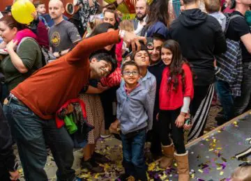 family taking a selfie in Garage exhibit with crowd behind them and remnants of new year's confetti on the ground