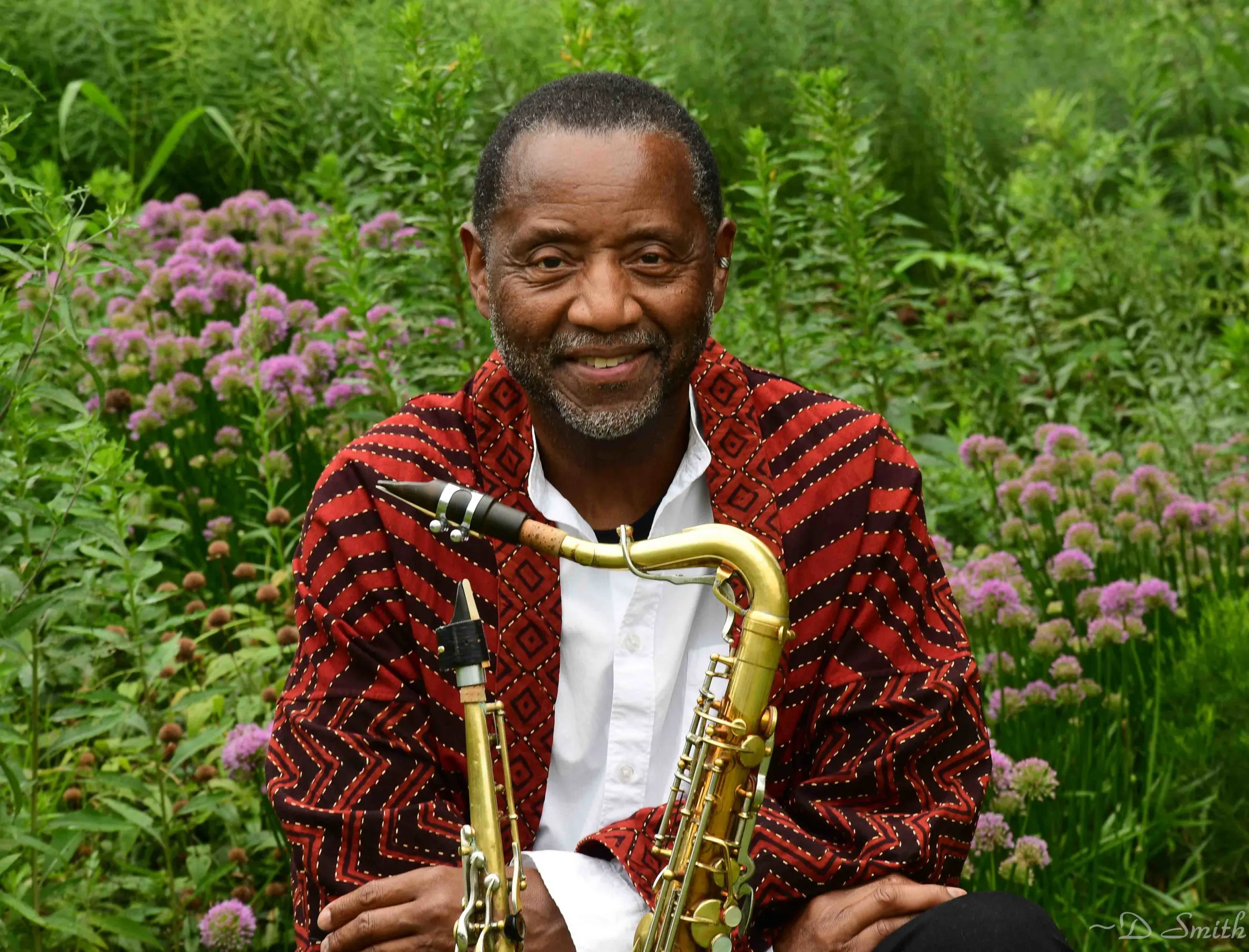 male in red sweater with saxophone in a field