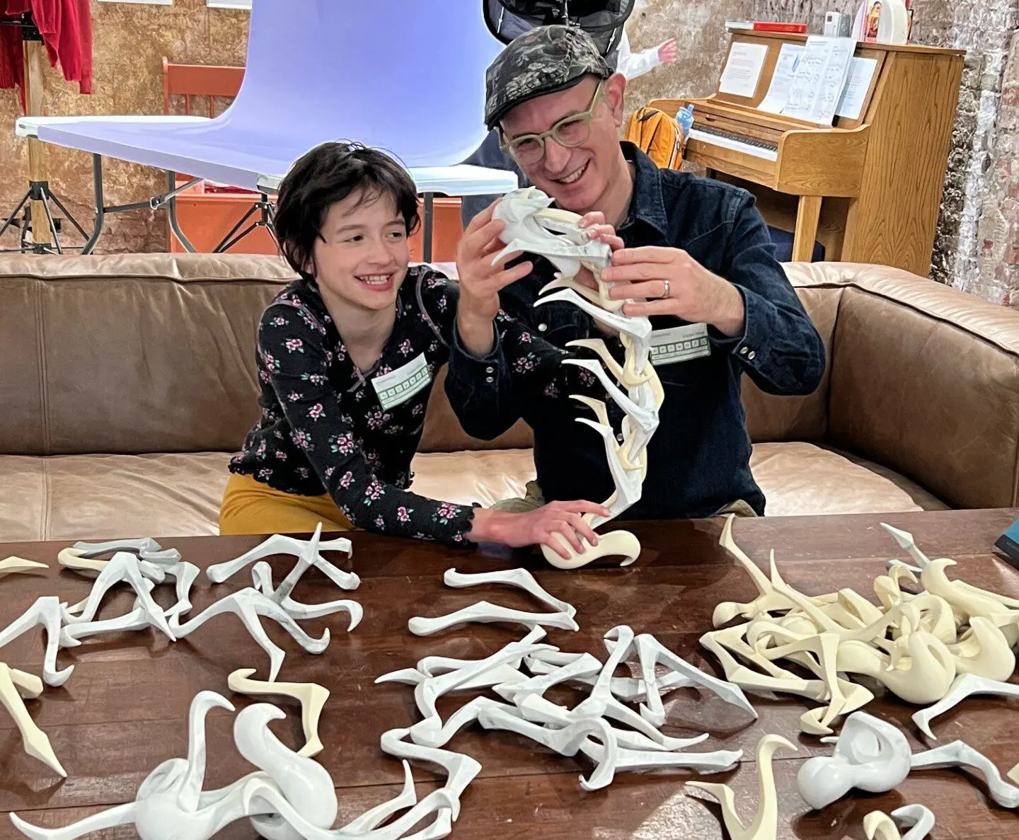 Teen and adult man exploring white sculptural pieces that look like bones