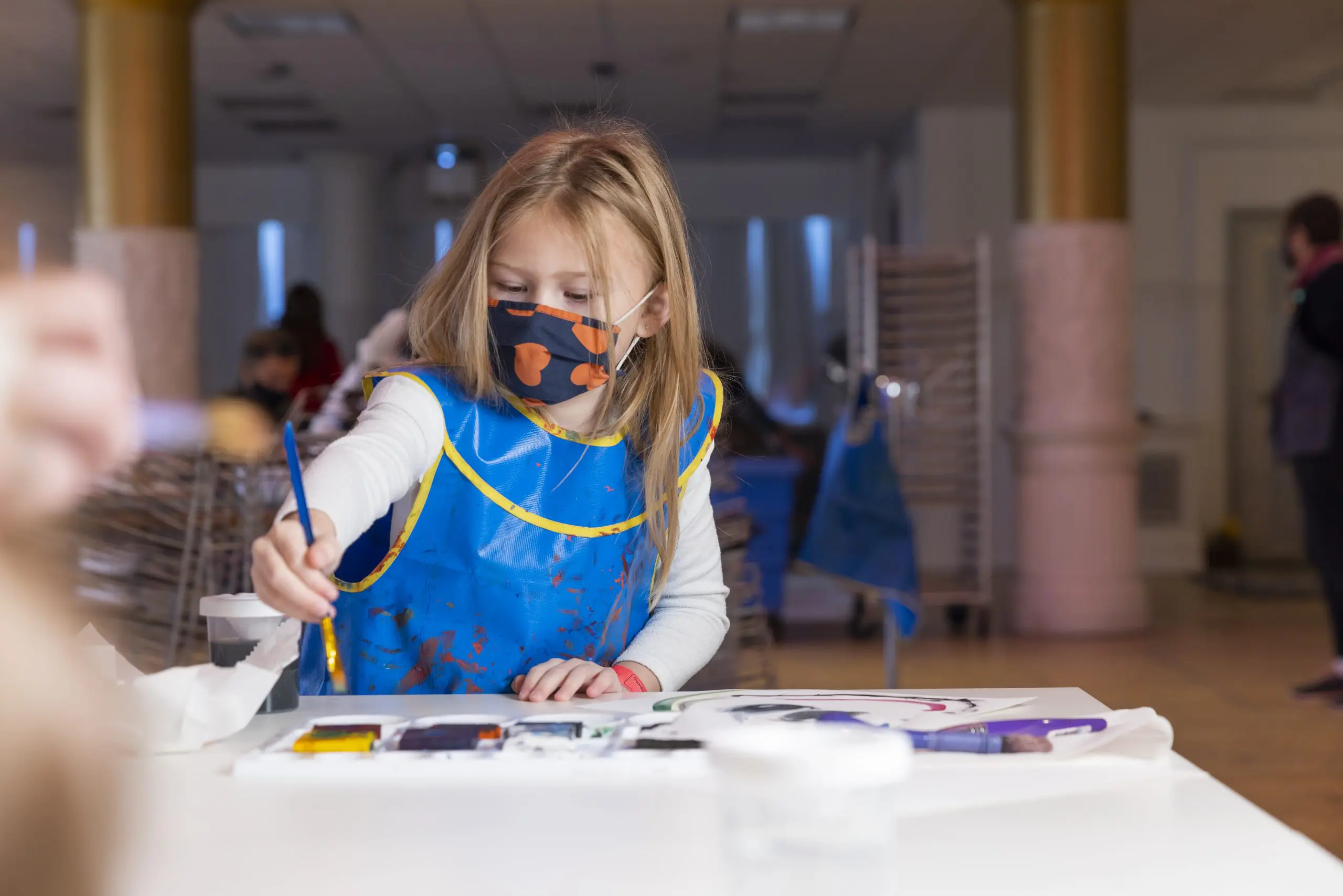 A child paints using a palette of colors