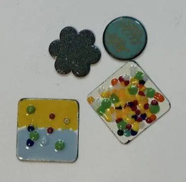 four small enameled pieces sit on a white surface