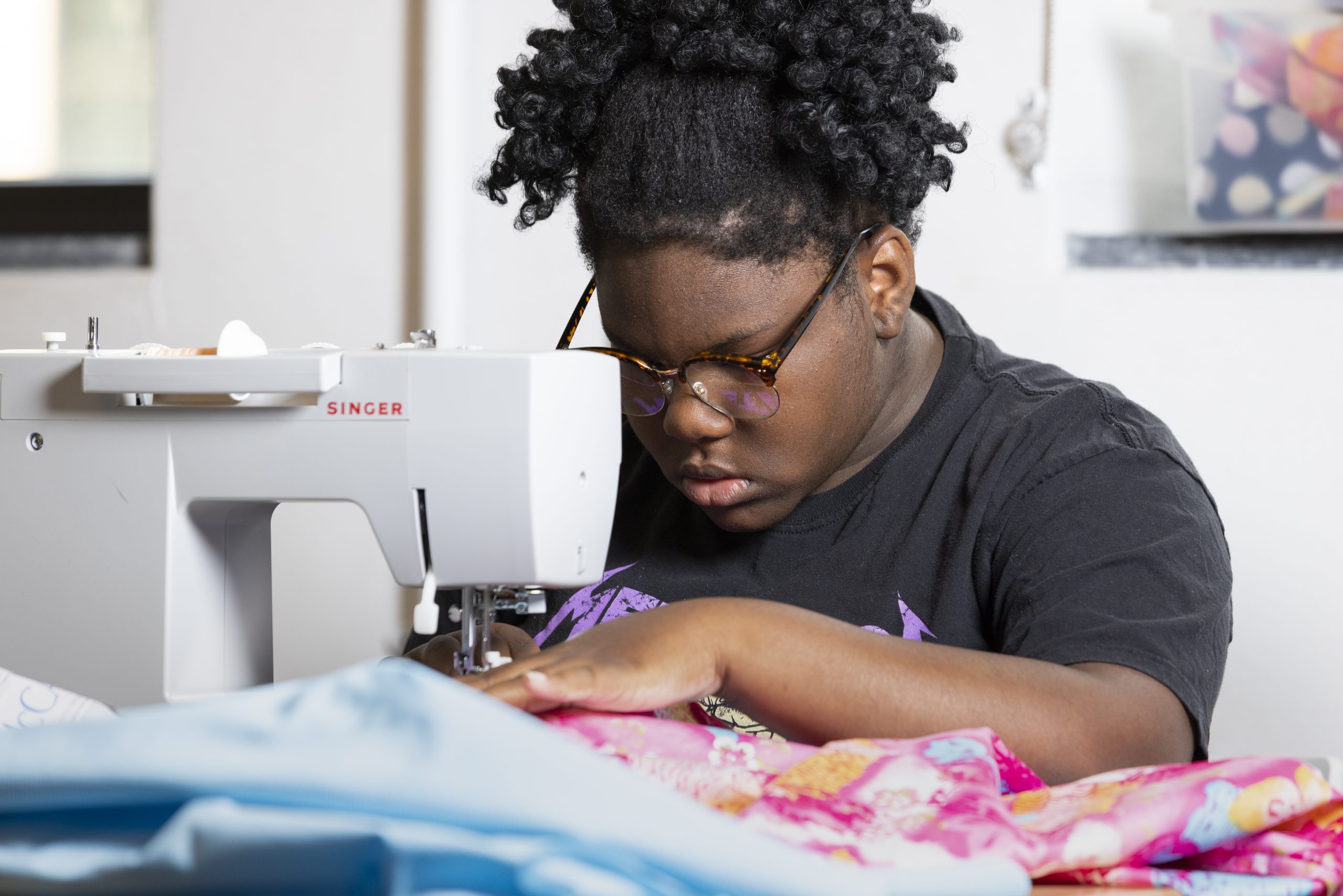 A child sews fabric using a sewing machine