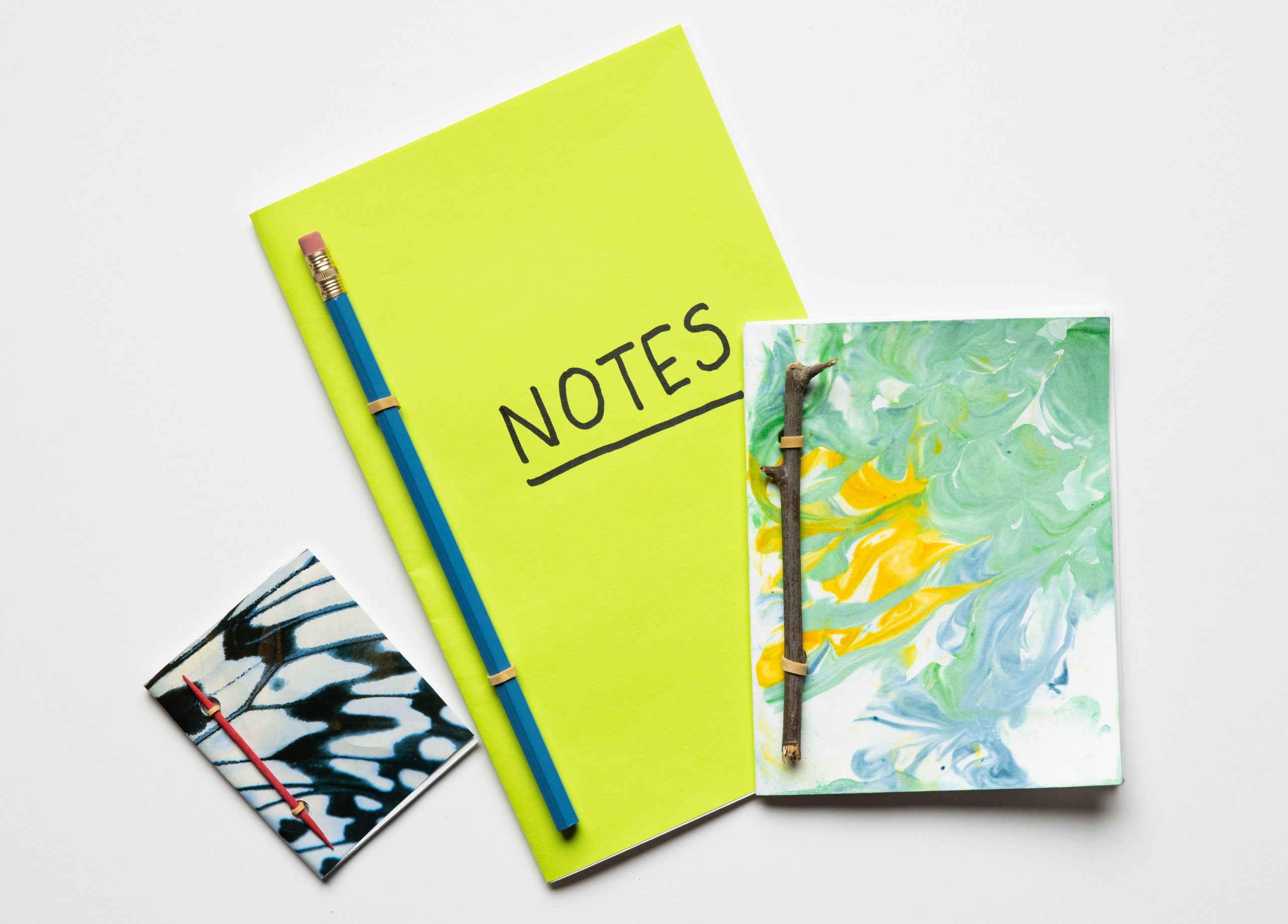 Three handmade notebooks of varying sizes on a white background.