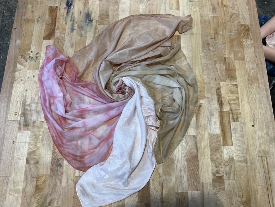 Four silk scarves, each a different neutral shade, are twisted into each other
