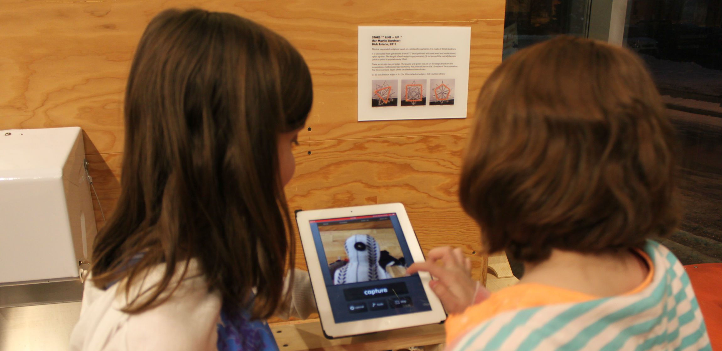 Two children use an iPad to record a frame of their animation