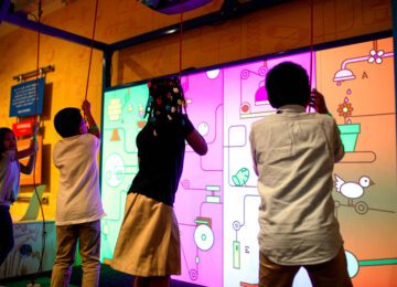 Four children pulling cords on a musical, digital cause-and-effect screen