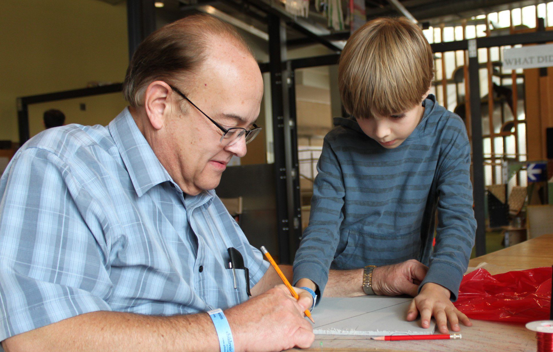 an older man and a child draw together on a piece of paper
