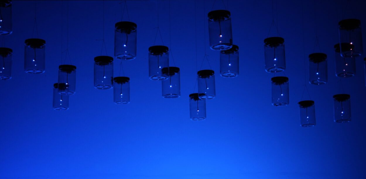 Multiple jars hanging from ceiling with led lights inside to simulate fireflies.